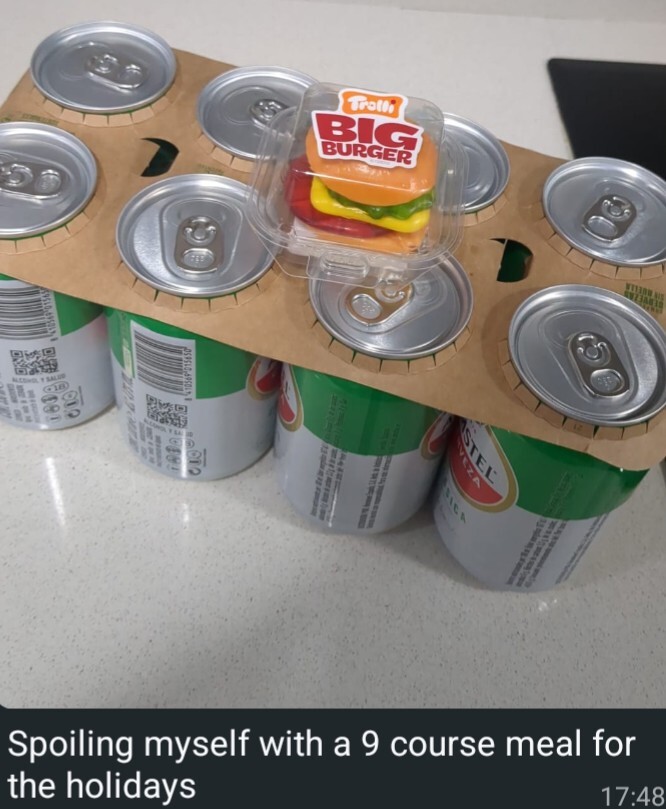 An eight pack of cheap beer cans and a tiny gummy candy burger. The caption reads "Spoiling myself with a 9 course meal for the holidays"