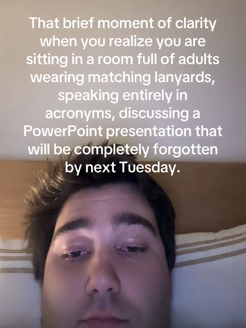 A selfie of a person with the caption “That brief moment of clarity when you realize you are sitting in a room full of adults wearing matching lanyards, speaking entirely in acronyms, discussing a PowerPoint presentation that will be completely forgotten by next Tuesday.”